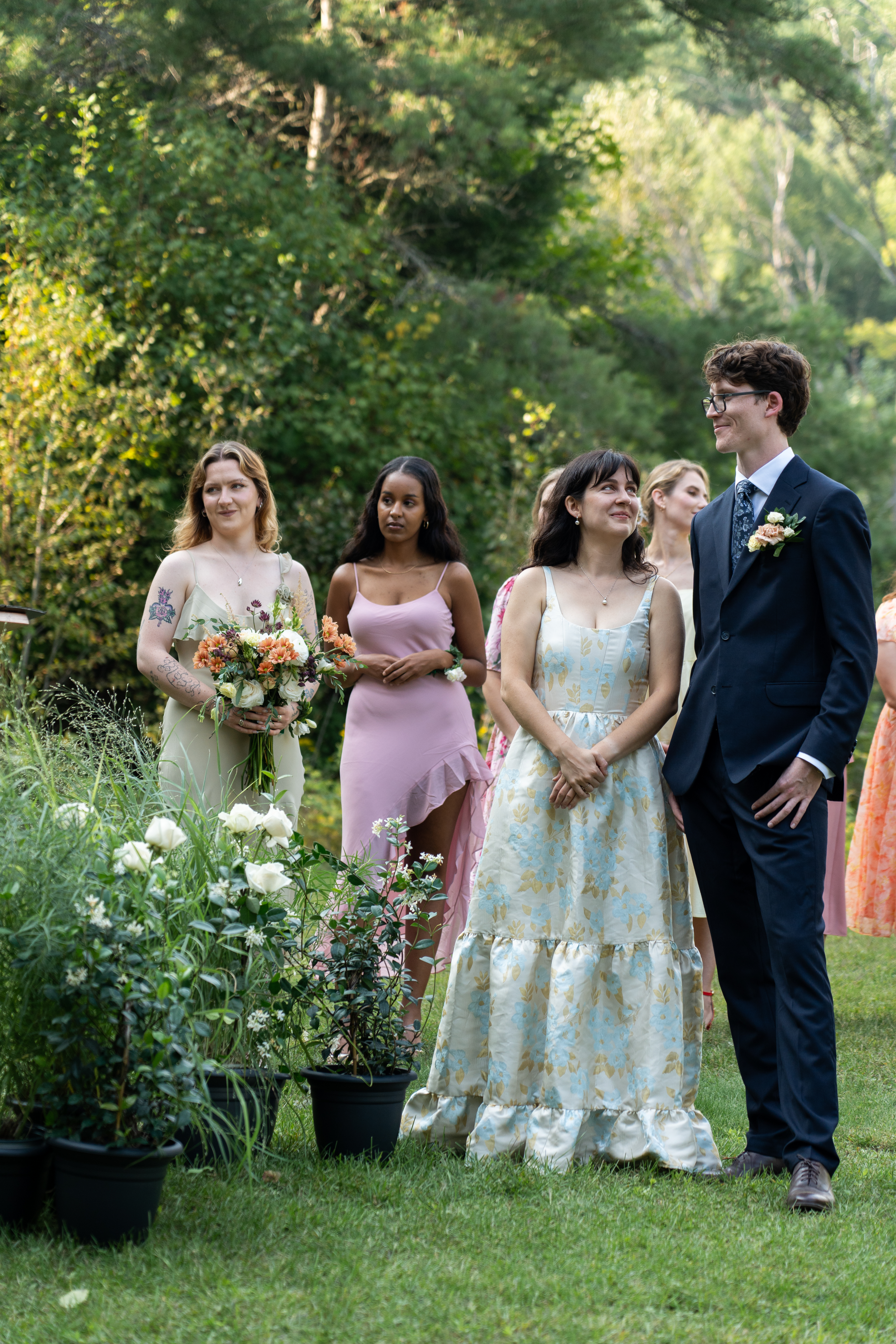 Bride and Groom stand side by side smiling at each other